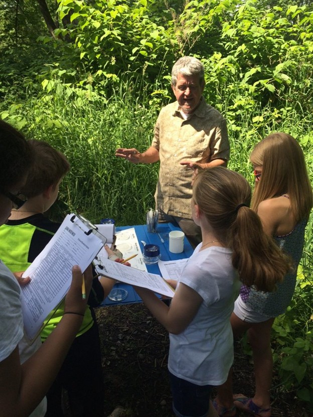 A man teaching children information about monitoring water quality